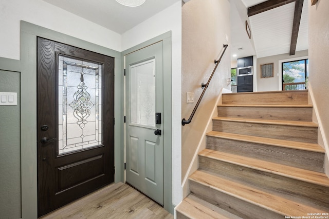 entrance foyer with light hardwood / wood-style floors and beamed ceiling