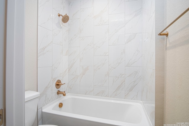 bathroom featuring toilet and tiled shower / bath