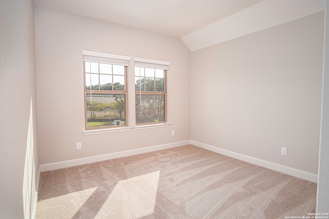 unfurnished room featuring lofted ceiling and light carpet