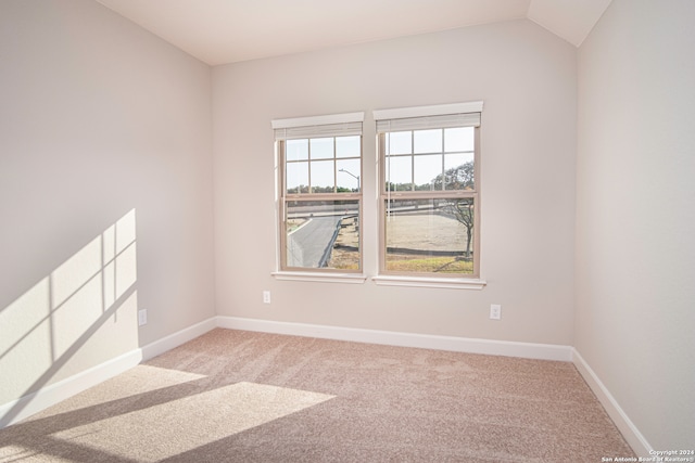 carpeted spare room with lofted ceiling