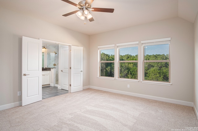 unfurnished bedroom featuring lofted ceiling, ceiling fan, connected bathroom, and dark colored carpet