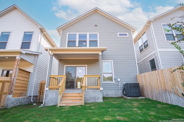 rear view of property with a yard and central AC unit