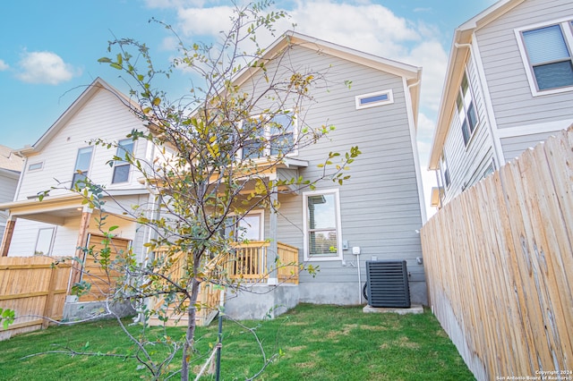 back of property with central AC and a lawn