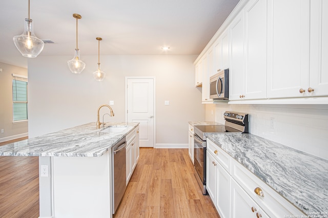 kitchen featuring appliances with stainless steel finishes, sink, decorative light fixtures, white cabinets, and a center island with sink