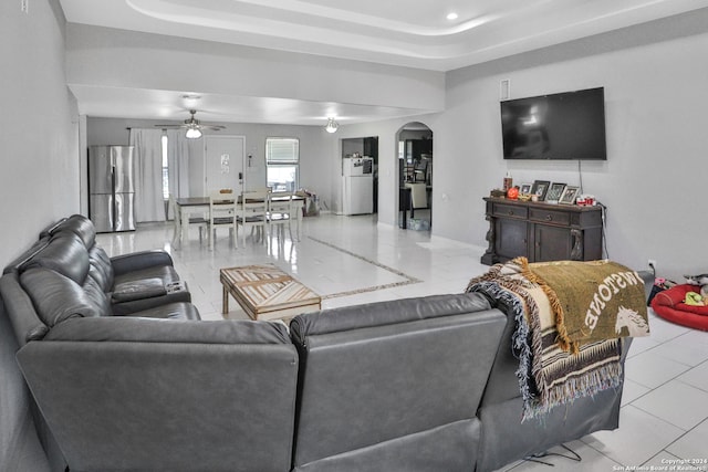 living room with ceiling fan and a raised ceiling