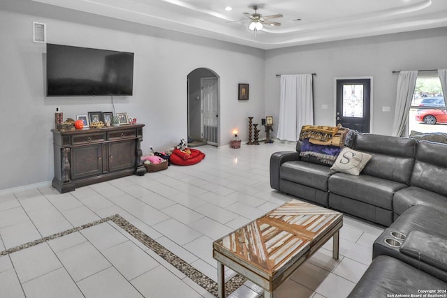 living room with ceiling fan, light tile patterned floors, and a raised ceiling