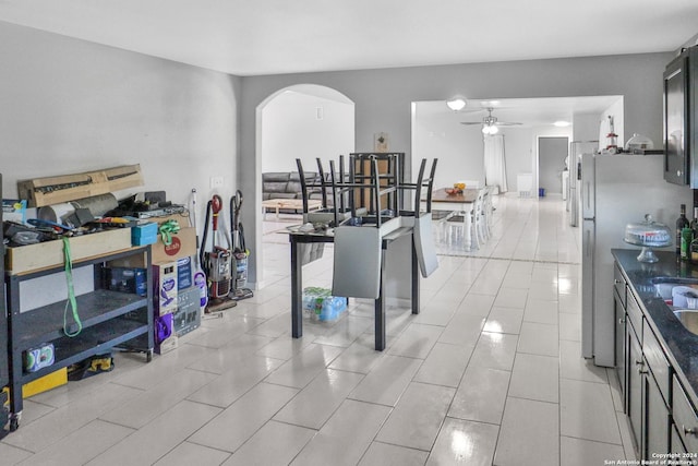 14024 Wisdom Rd, Atascosa, TX 78002 - interior space featuring arched walkways, a ceiling fan, light tile patterned flooring, and freestanding refrigerator