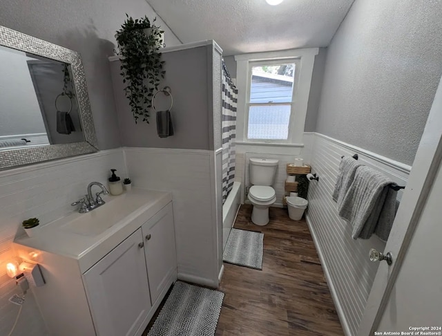 bathroom with hardwood / wood-style flooring, toilet, curtained shower, vanity, and a textured ceiling