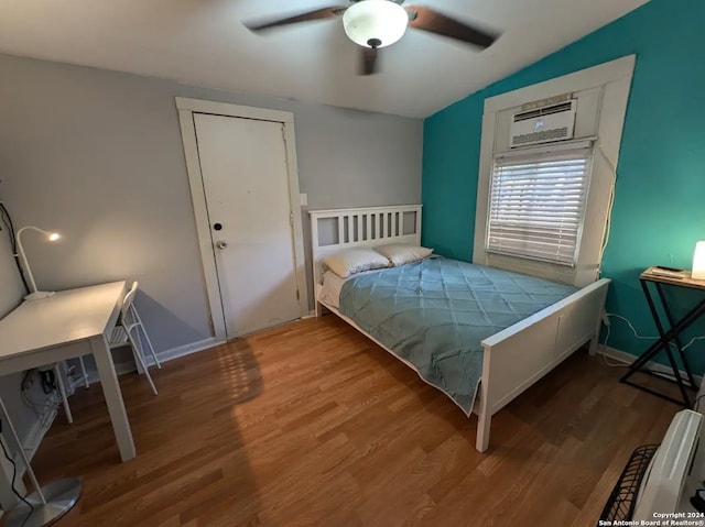 bedroom with a wall mounted air conditioner, hardwood / wood-style flooring, vaulted ceiling, and ceiling fan