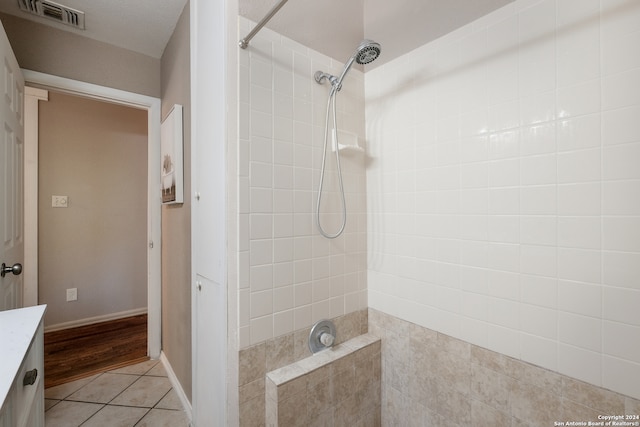 bathroom with a tile shower, tile patterned flooring, and vanity