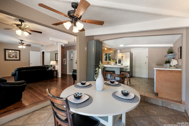 dining space with beam ceiling, hardwood / wood-style floors, a textured ceiling, and ceiling fan