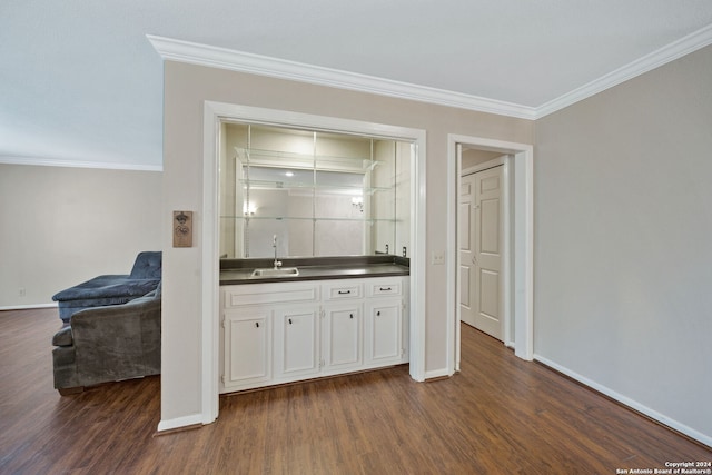 bar with dark wood-type flooring, ornamental molding, sink, and white cabinets