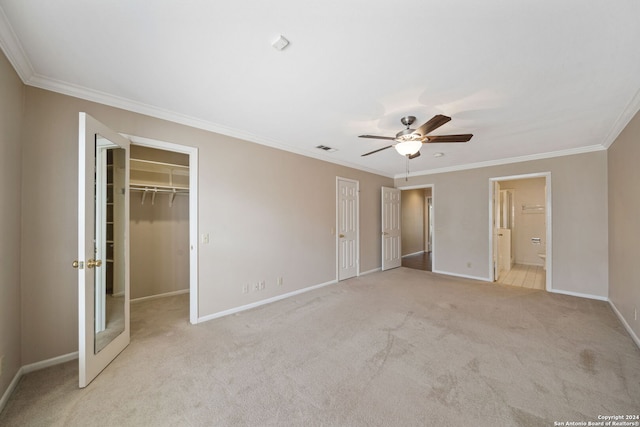 unfurnished bedroom with light carpet, a walk in closet, ceiling fan, connected bathroom, and crown molding