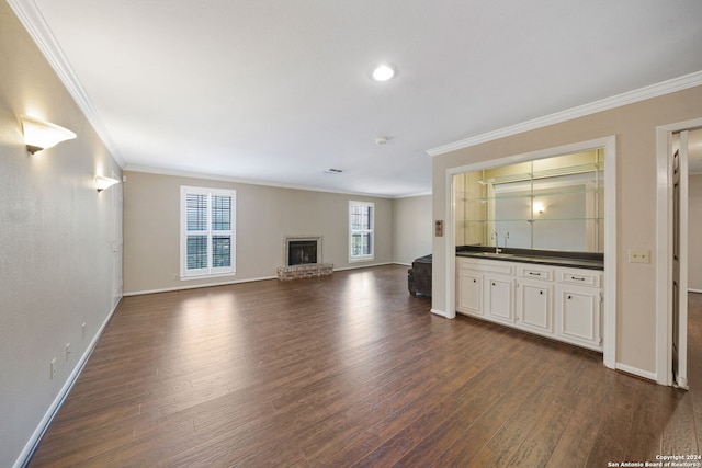 unfurnished living room with ornamental molding, indoor wet bar, a fireplace, and dark hardwood / wood-style flooring