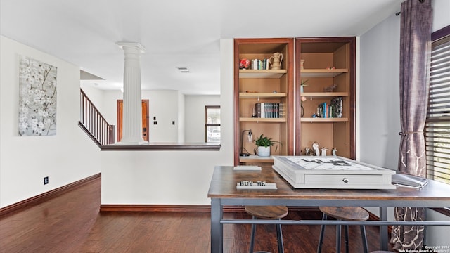 home office featuring dark wood-type flooring, decorative columns, and plenty of natural light