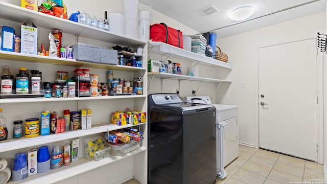 laundry room featuring independent washer and dryer, a textured ceiling, and light tile patterned flooring