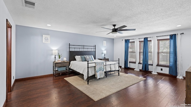 bedroom with a textured ceiling, ceiling fan, and dark hardwood / wood-style flooring