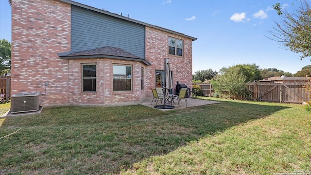 back of house with cooling unit, a patio area, and a lawn