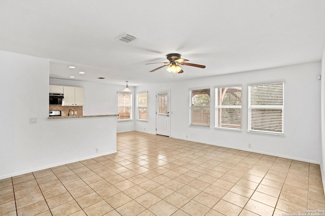 unfurnished living room with sink, ceiling fan, and light tile patterned floors