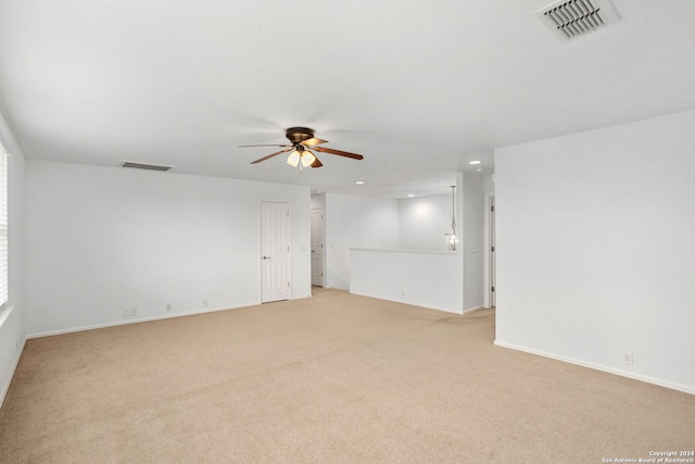 carpeted empty room featuring ceiling fan with notable chandelier