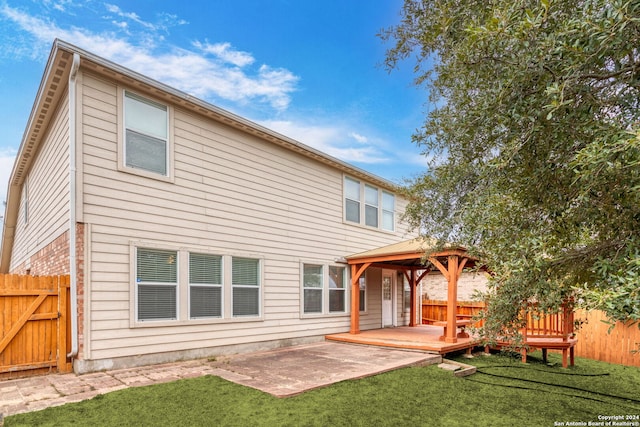 back of property featuring a gazebo, a deck, a lawn, and a patio area