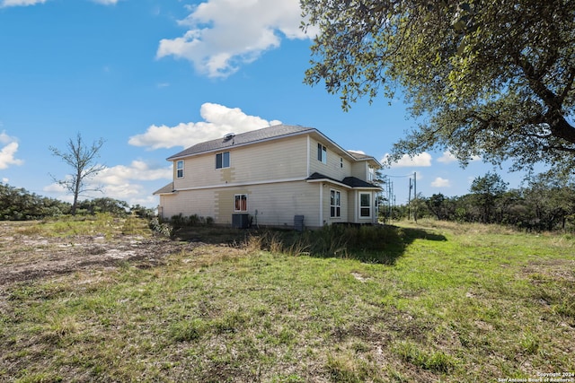 back of property with cooling unit and a lawn