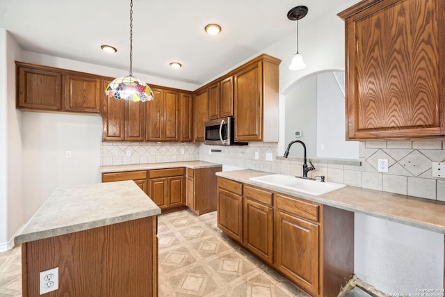 kitchen with backsplash, a kitchen island, sink, and hanging light fixtures