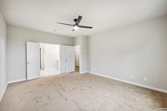 unfurnished bedroom featuring ensuite bath, ceiling fan, and light carpet