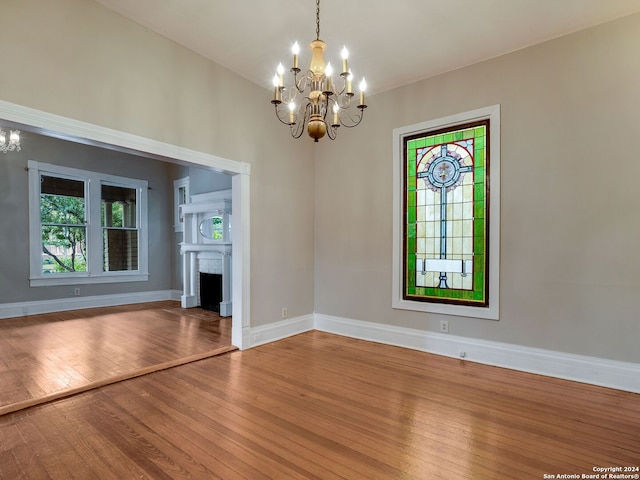 spare room featuring hardwood / wood-style flooring, vaulted ceiling, and a notable chandelier