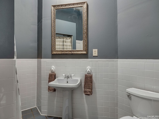 bathroom with sink, toilet, and tile walls