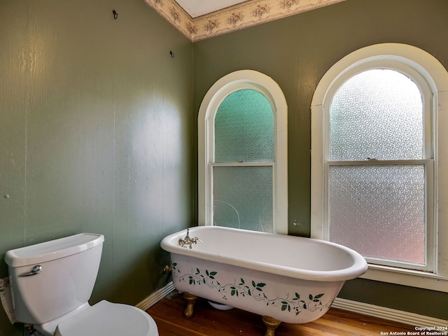 bathroom featuring hardwood / wood-style floors, toilet, and a tub to relax in