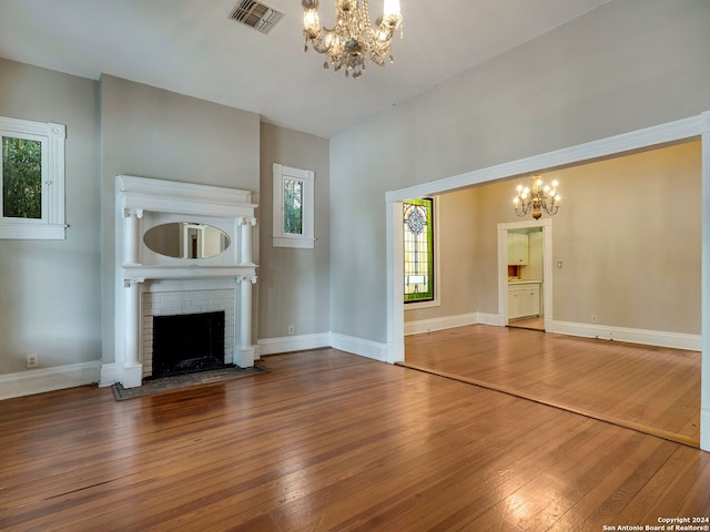 unfurnished living room featuring plenty of natural light, an inviting chandelier, and hardwood / wood-style flooring