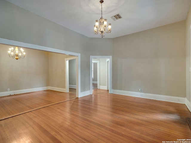 unfurnished room featuring hardwood / wood-style floors and a notable chandelier