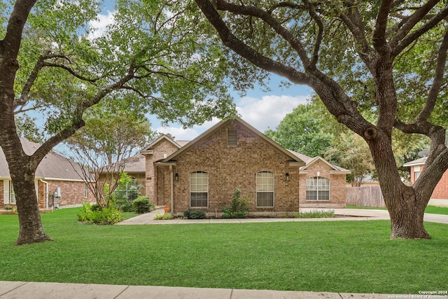 view of front facade featuring brick siding, fence, and a front yard