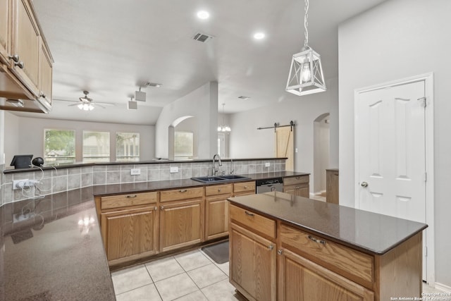 kitchen with sink, a barn door, ceiling fan, stainless steel dishwasher, and tasteful backsplash