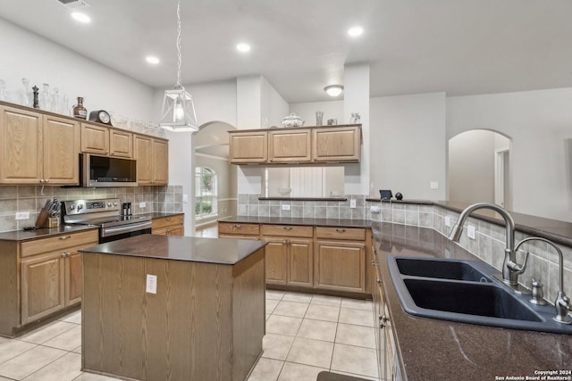 kitchen with a sink, stainless steel appliances, light tile patterned floors, and arched walkways