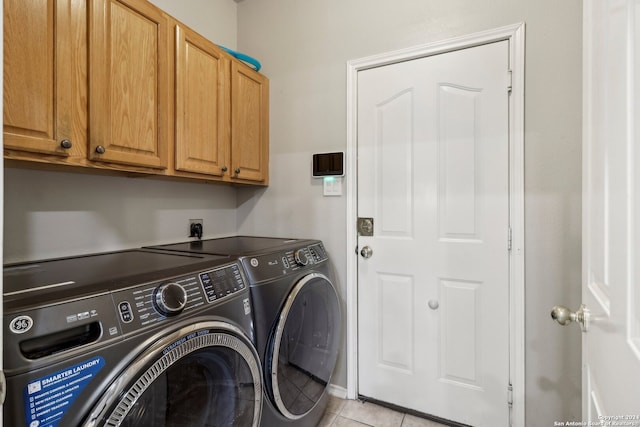 clothes washing area with light tile patterned floors, separate washer and dryer, and cabinets