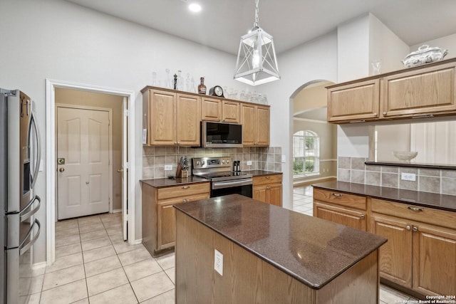 kitchen with arched walkways, decorative backsplash, stainless steel appliances, a kitchen island, and light tile patterned flooring
