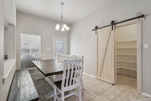 tiled dining space featuring an inviting chandelier and a barn door