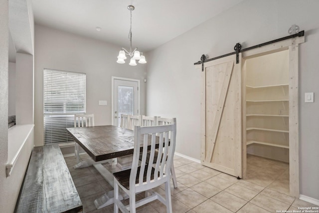 dining space featuring light tile patterned floors, a chandelier, a barn door, and baseboards