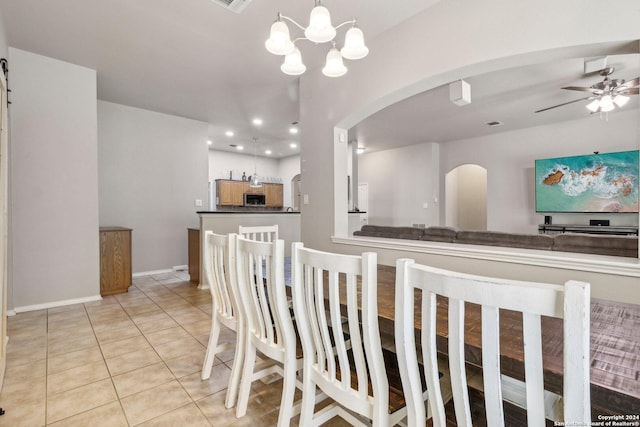 dining room with recessed lighting, light tile patterned floors, baseboards, arched walkways, and ceiling fan with notable chandelier