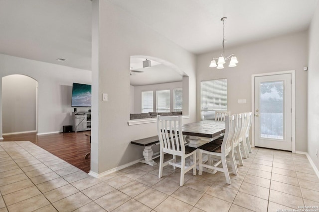 tiled dining room with visible vents, baseboards, a notable chandelier, and arched walkways