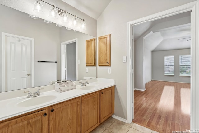 bathroom with vaulted ceiling, tile patterned flooring, double vanity, and a sink