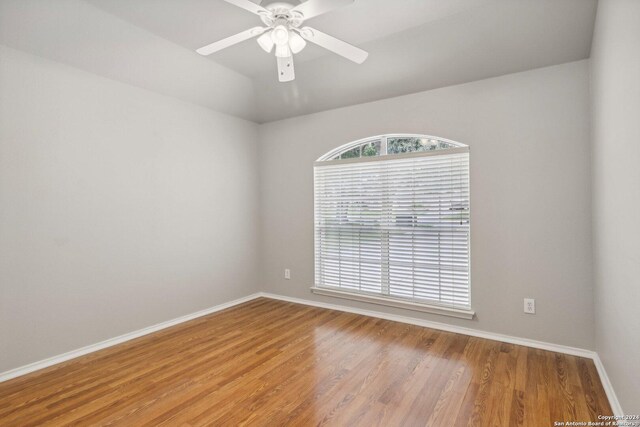 unfurnished room featuring lofted ceiling, wood finished floors, a ceiling fan, and baseboards
