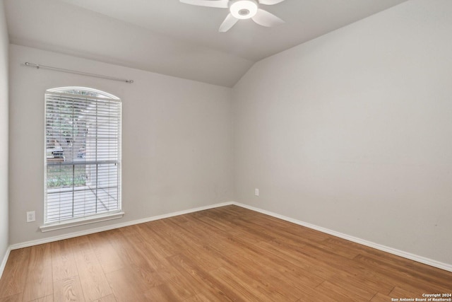spare room featuring ceiling fan, light wood finished floors, vaulted ceiling, and baseboards