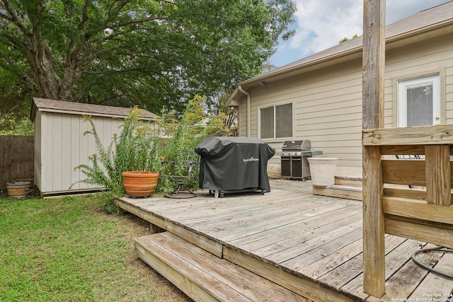 wooden terrace with an outdoor structure, a shed, area for grilling, and fence