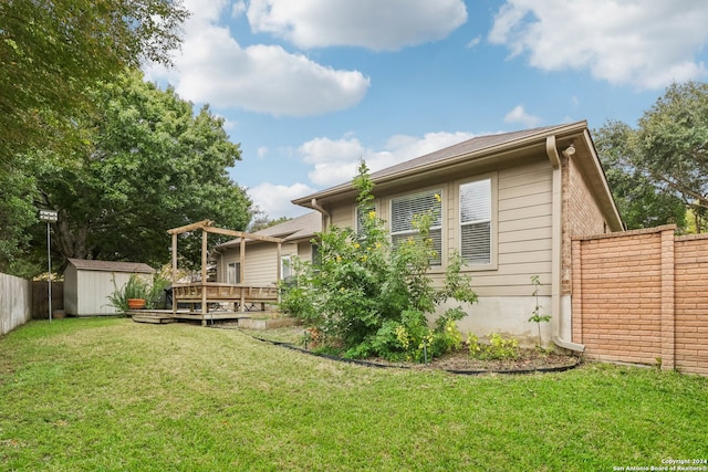 rear view of property with a storage unit, a deck, and a yard