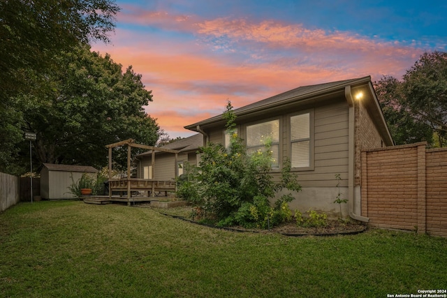 back house at dusk featuring a storage unit and a yard