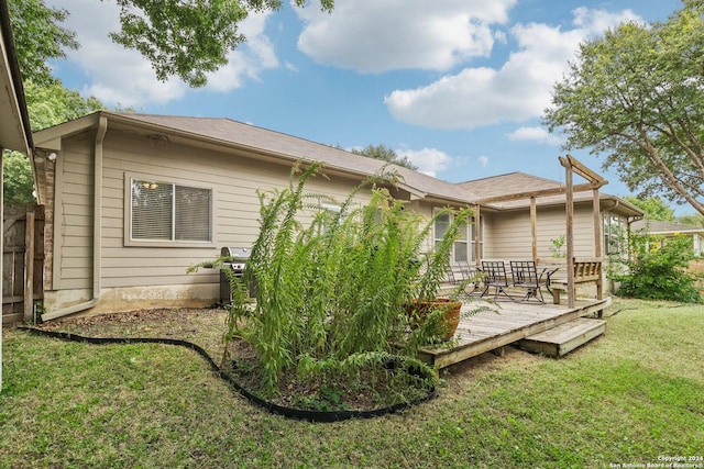 back of house with fence, a wooden deck, and a yard