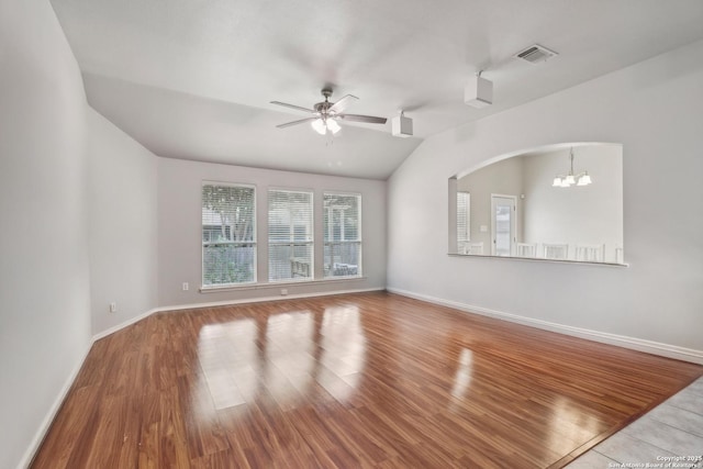 unfurnished living room with wood finished floors, arched walkways, ceiling fan with notable chandelier, baseboards, and visible vents